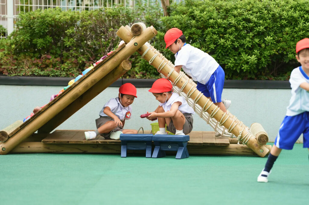 園庭の木製遊具で遊ぶ子どもたち
