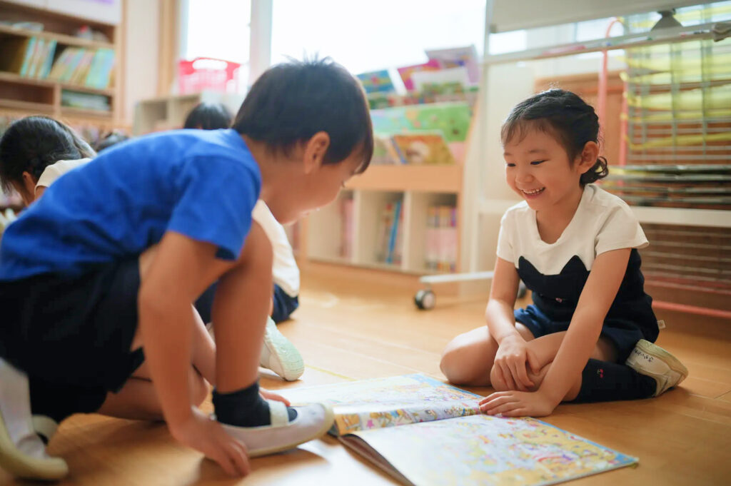 友だちと絵本を開く子どもたち