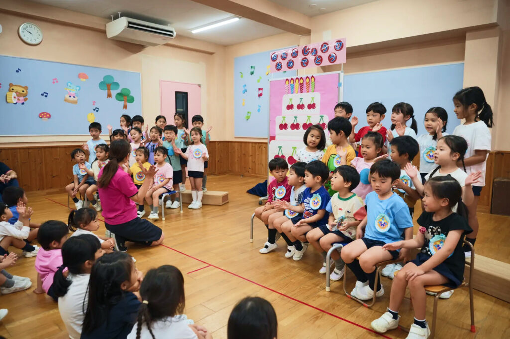 お誕生会で先生と一緒に歌や手遊びを楽しむ子どもたち