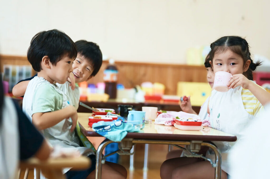 友だちとテーブルを囲んで給食を食べる子どもたち