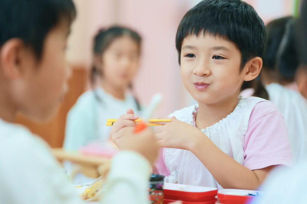 友だちと一緒に給食を食べる園児