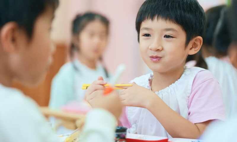 友だちと一緒に給食を食べる園児